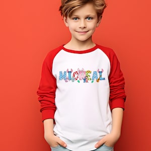 May include: A white and red raglan-style shirt with the name "MICHAEL" printed across the chest in colorful, cartoon-style letters. The letters are decorated with various cartoon characters and objects.