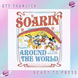 May include: DTF transfer featuring a colorful illustration of Disney characters Pluto, Donald Duck, Goofy, and Mickey Mouse hang gliding. The text reads "Soarin' Around the World" with "Sky Commander" above and "Fearless Pursuit of Adventure" below. The words "DTF TRANSFER" and "READY TO PRESS" are also included.