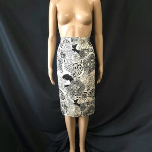 Puede incluir: Una falda lápiz de talle alto y largo hasta la rodilla con un estampado gráfico en blanco y negro. El patrón consiste en intrincados motivos circulares, detalles arquitectónicos ornamentados y elementos de texto manuscrito dispersos por toda la tela.