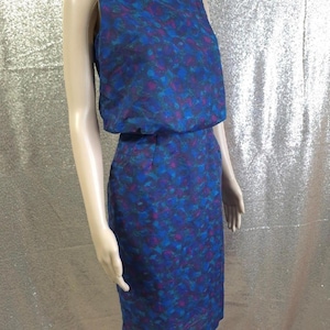 May include: A vintage two-piece dress with a sleeveless top and a knee-length skirt. The dress has a blue, purple, and teal floral pattern. The top has a square neckline and a gathered waist. The skirt is a straight, fitted style, typical of the era.