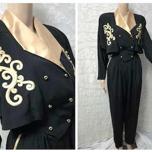 May include: A black vintage jumpsuit with gold detailing. The jacket has gold embroidered patterns and gold buttons. The collar and trim are gold. The high-waisted trousers have a pleated front, creating a classic silhouette.