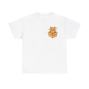Peut inclure: T-shirt blanc avec un motif de chat de dessin animé. Le chat est orange et se trouve dans une boîte marron. Le motif comprend des formes géométriques vertes, jaunes et bleues. Un design amusant et ludique.