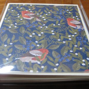 May include: A stack of blank greeting cards with a blue background and a repeating pattern of white berries, green leaves, and red birds. The cards are packaged in a clear plastic sleeve.