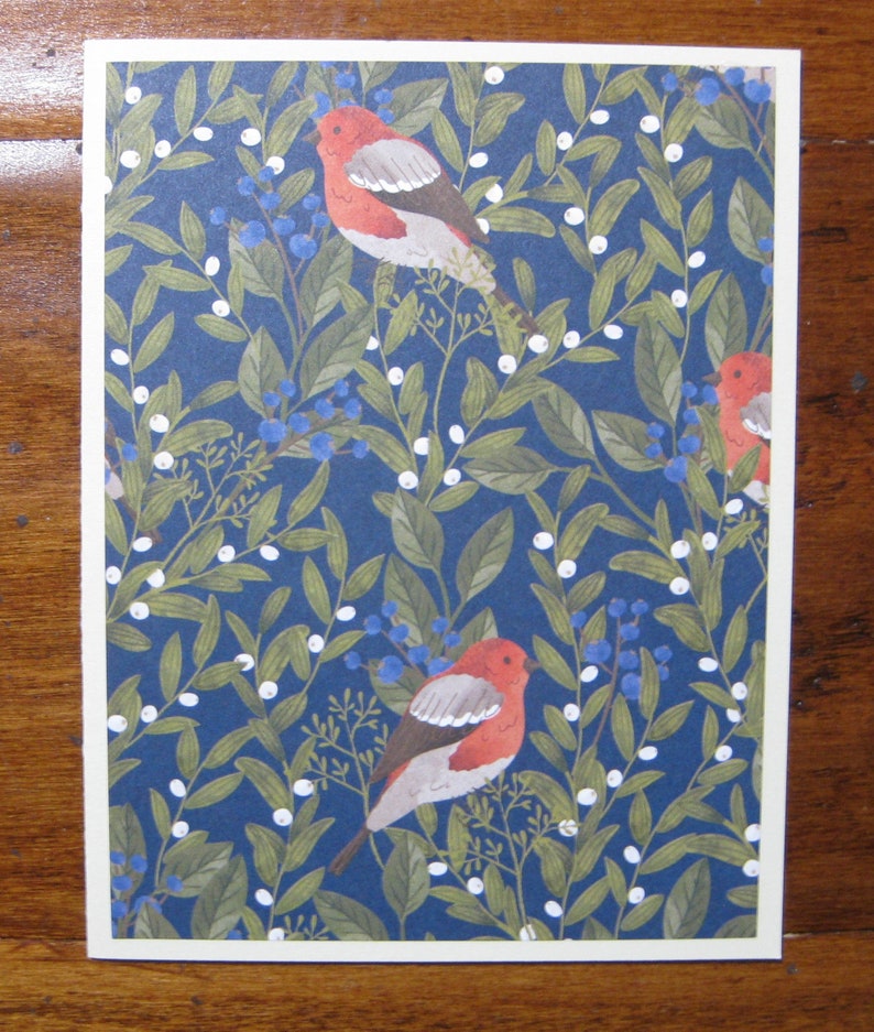 May include: A blue background with a repeating pattern of white berries, green leaves, and red birds. The birds have white markings on their wings and are perched on the branches.