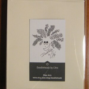 May include: A white card with a black and white doodle of a smiling face with a large, curly afro. The card has the text "Doodleheadz by CAro" and "Fiber Arts www.etsy.com/shop/doodleheadz" printed on it.
