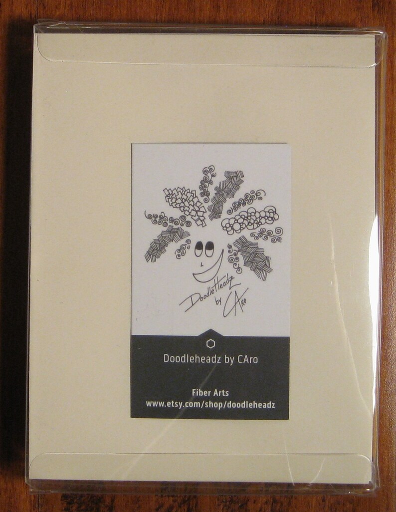 May include: A white card with a black and white doodle of a smiling face with a large, curly afro. The card has the text "Doodleheadz by CAro" and "Fiber Arts www.etsy.com/shop/doodleheadz" printed on it.