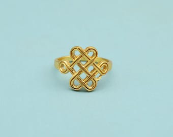 May include: A gold ring with an elaborate knot design. The ring showcases a series of interwoven loops, forming a symmetrical pattern. The ring is set against a light blue backdrop, accentuating the ring's details.