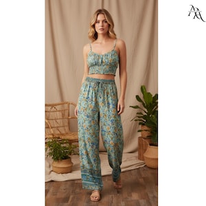 May include: A two-piece set with a floral pattern in blue, yellow, and green. The set comprises a crop top with thin straps and wide-leg trousers with a drawstring waist. The outfit is made of a lightweight fabric, ideal for warm weather.