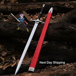 Puede incluir: Una espada plateada y negra con una vaina roja descansa sobre un lecho de troncos. La espada tiene una hoja larga y afilada y un mango negro. También hay una pequeña figura de un personaje sosteniendo una espada.