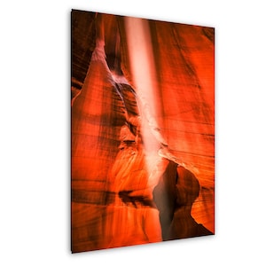 May include: A vertical print of a red rock canyon with a beam of sunlight shining down. The canyon walls are textured and have shadows. The overall colour palette is warm, with shades of red and orange.