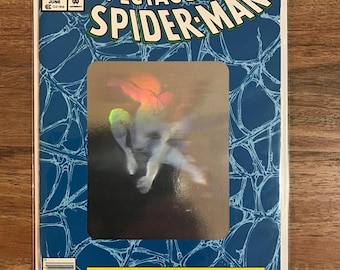 May include: A comic book cover for "The Spectacular Spider-Man" featuring the title in large, white, 3D lettering. The cover is blue with a web pattern and a central image of Spider-Man. Text includes "30th Anniversary Special" and "Marvel Comics".
