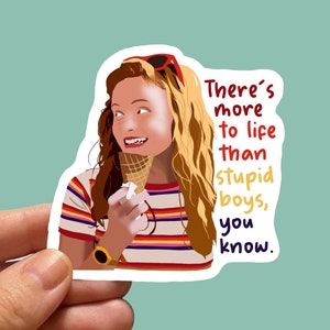 May include: A sticker featuring a cartoon illustration of a girl with long, wavy auburn hair, wearing a striped shirt and sunglasses. She holds an ice cream cone and the text reads, "There's more to life than stupid boys, you know."