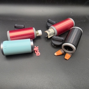 以下が含まれることがあります： 赤、黒、ターコイズ色の円筒形の容器のコレクション。銀色のアクセントが付いています。1つの容器には丸められた紙幣が入っており、他は空か小さなオブジェクトが入っています。黒い蓋とキャンディーコーンも表示されています。