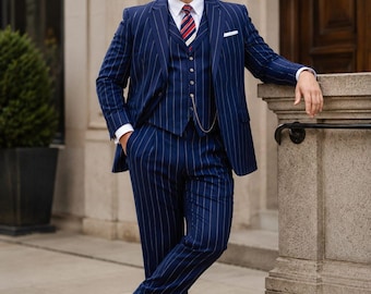 May include: A navy blue three-piece suit with white pinstripes, featuring a single-breasted jacket, a matching vest with a gold pocket watch chain, a white dress shirt, a red, white, and blue striped tie, and black leather dress shoes.