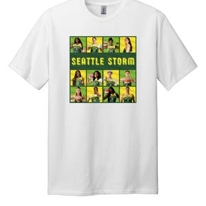 Może przedstawiać: Biała koszulka z krótkim rękawem z centralnym nadrukiem graficznym drużyny koszykarskiej Seattle Storm. Wzór zawiera siatkę jedenastu indywidualnych portretów zawodniczek w zielono-żółtych strojach oraz napis SEATTLE STORM w kolorze żółtym.