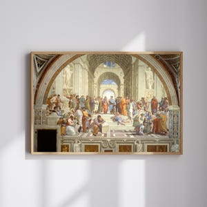 Peut inclure: Une impression encadrée de L'École d'Athènes de Raphaël, représentant un grand groupe de philosophes dans un cadre architectural classique avec des plafonds voûtés, des colonnes en marbre et des statues, dans des tons terreux et bleus.