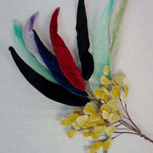 May include: A collection of colorful velvet leaves in shades of black, red, blue, purple, green, and light green, arranged with a cluster of yellow velvet flowers. The leaves are long and slender, and the flowers have a soft, textured appearance.