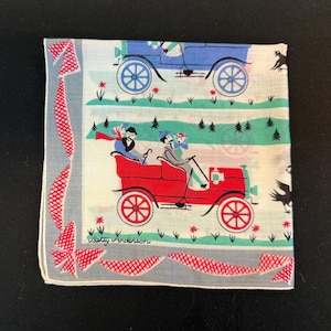 May include: A vintage handkerchief with a blue and red car design. The handkerchief has a white background with green and red accents. The text "Betty Anderson" is printed in the bottom left corner.