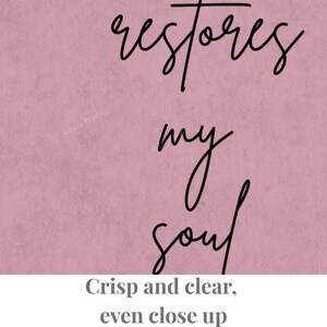 A dusty rose pink wall art print featuring the black cursive text "restores my soul" centered on the page. The design has a matte, textured appearance with clean, legible lettering that stands out against the solid colored background.