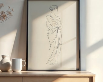 May include: Black framed art print featuring a minimalist line drawing of a draped figure. The artwork is in black against a cream background. The print is displayed on a wooden cabinet, with a white mug and vase.