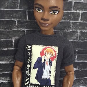 K&ouml;nnte beinhalten: Ein schwarzes T-Shirt mit einem Grafikdruck eines Comic-Charakters in einem blauen Anzug. Der Text auf dem Shirt lautet "Shumei Sasaki" und enth&auml;lt japanische Schriftzeichen.