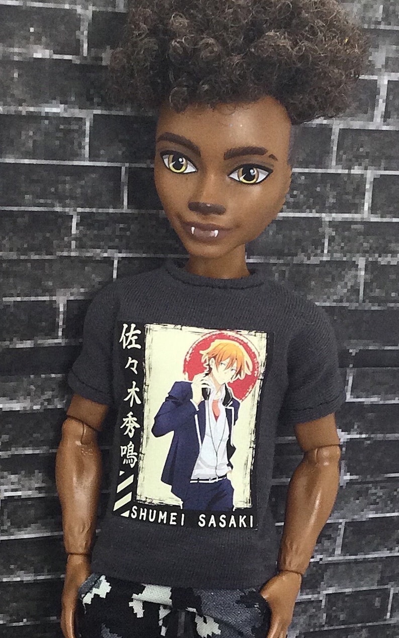 K&ouml;nnte beinhalten: Ein schwarzes T-Shirt mit einem Grafikdruck eines Comic-Charakters in einem blauen Anzug. Der Text auf dem Shirt lautet "Shumei Sasaki" und enth&auml;lt japanische Schriftzeichen.