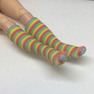 Pode incluir: Um par de meias de riscas arco-íris até ao joelho. As meias são feitas de um material macio e elástico, perfeitas para adicionar um toque de cor a qualquer roupa.