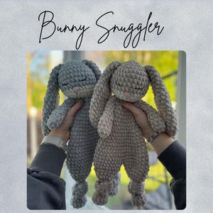 Op de afbeelding: Twee handgemaakte gehaakte konijnknuffels in grijstinten en taupe worden omhoog gehouden. De konijnen hebben lange, slappe oren, gesloten ogen en een zacht, getextureerd uiterlijk. De tekst "Bunny Snuggler" en "Pattern" is cursief geschreven.