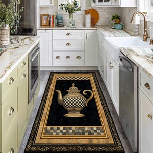 May include: A rectangular kitchen rug featuring a black background with a gold-framed design. The rug showcases a detailed teapot with a checkered pattern and a crown. The border includes a checkered pattern and ornate gold detailing.