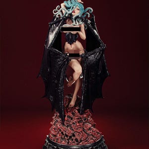 Peut inclure: Figurine détaillée d'une femme aux cheveux bleus et aux ailes noires en forme de chauve-souris. La figurine est posée sur une base rouge texturée avec une bordure argentée. Elle porte un corset noir.