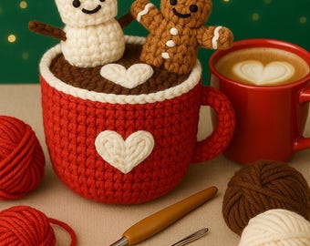 May include: A red crocheted mug with a white heart design, holding a snowman and gingerbread man. A red mug with latte art, yarn, crochet hook, and needles are also present. The theme is Christmas and crochet.