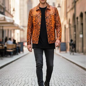 May include: A person wearing an orange and brown snakeskin-patterned jacket over a black t-shirt and dark grey jeans. The person is walking down a cobbled street. Black boots complete the outfit.