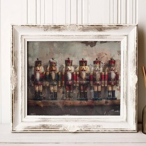 May include: A framed print featuring six decorative nutcrackers in red, white, and gold uniforms. The framed print is white with ornate detailing. A brown glass bottle with reeds is to the right of the frame.