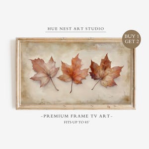 May include: A rectangular framed digital artwork titled HUE NEST ART STUDIO featuring three brown maple leaves on a beige background. The frame includes text stating BUY 1 GET 2 and PREMIUM FRAME TV ART FITS UP TO 85 inches.