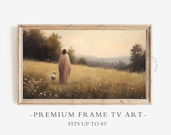 May include: A framed landscape print depicts a figure in a flowing robe walking with a lamb through a field of wildflowers. The artwork is set against a backdrop of rolling hills and a soft, overcast sky. The frame is a light wood color. The text at the bottom reads: "-PREMIUM FRAME TV ART- FITS UP TO 85"