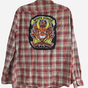 May include: Red and beige plaid button-down shirt with a large patch on the back. The patch features a devil graphic with the text "WHITE ZOMBIE" and "LA SEXORCISTO DEVIL MUSIC VOL. 1".