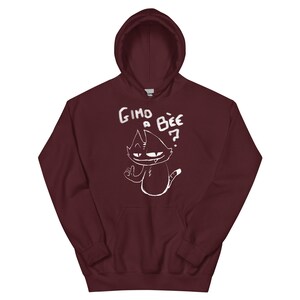 May include: A maroon hoodie with a white cartoon cat graphic and the text "Gimo a Bee?". The hoodie has a drawstring hood and a front pocket. The cat graphic is a simple, cartoonish design.