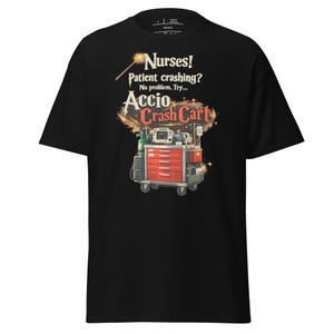 May include: Black t-shirt with a graphic featuring a red crash cart and the text "Nurses! Patient crashing? No problem. Try... Accio Crash Cart." The design includes a wand and sparkling effects.