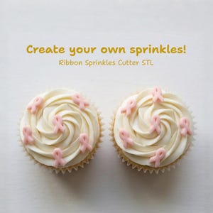 May include: Two cupcakes with white frosting, each topped with pink ribbon-shaped sprinkles. The cupcakes sit on a white surface. Text in the image reads: "Create your own sprinkles! Ribbon Sprinkles Cutter STL."