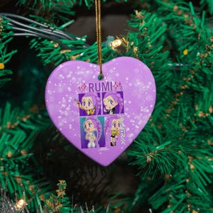 May include: A heart-shaped Christmas ornament with a purple background and a gold string for hanging. The ornament features the word "RUMI" and four anime-style illustrations of a character with purple hair. The Japanese text is visible on the right side.