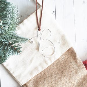 May include: A white and brown stocking with a burlap bottom. A silver wire initial "B" hangs from a brown leather cord.