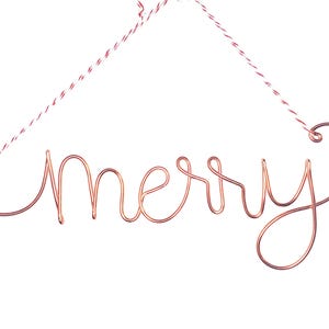 Può includere: Un ornamento in filo di rame a forma della parola "merry" appeso a uno spago rosso e bianco.