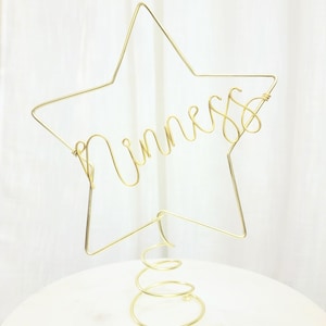 May include: Gold wire star tree topper with the word "Princess" written in the wire. The star is attached to a gold spring.