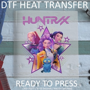 May include: DTF heat transfer featuring the word "HUNTRAX" above a graphic of three animated women inside a purple star. A blue cartoon cat is in the foreground. The text "READY TO PRESS" is at the bottom.