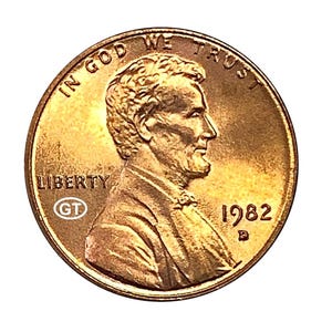 Puede incluir: Una moneda de un centavo estadounidense de 1982, de color cobre. El anverso presenta el perfil de un hombre, las palabras "IN GOD WE TRUST" y "LIBERTY". También es visible el año "1982".