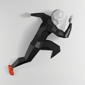 以下が含まれることがあります： 動きのあるランナーの幾何学的なローポリゴンフィギュア。フィギュアは主に黒色で、灰色の頭と赤い靴が一つ。ランナーは白い背景を背景に描かれており、ダイナミックなポーズを強調しています。