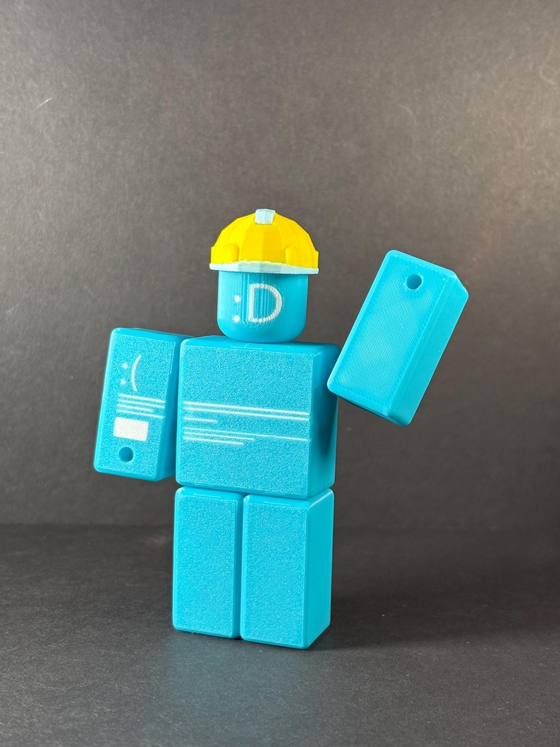 May include: A turquoise block figure with a yellow hard hat. The figure has a smiley face and the letter "D" on its head. The figure's arms are outstretched, and it has a sad face on one arm.