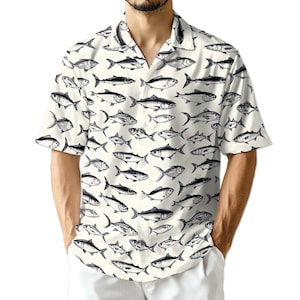May include: Short-sleeved shirt with a cream-coloured background and a repeating pattern of black and white fish illustrations. The shirt has a classic collar and is made of a lightweight fabric.