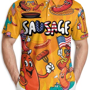 Op de afbeelding: Gele polo met een herhaald patroon van cartoonworsten, grillelementen en Amerikaanse vlaggen. Het woord "SAUSAGE" staat in witte blokletters. De polo heeft een kraag en korte mouwen.