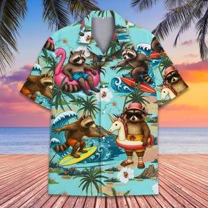 Puede incluir: Una camisa de manga corta con un diseño tropical. La camisa presenta mapaches disfrutando de una escena de playa, surfeando y relajándose en flotadores. El fondo es azul claro con palmeras, olas y una puesta de sol.